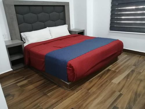 a large bed in a room with a wooden floor at Hotel ANB Aeropuerto Guadalajara in Guadalajara