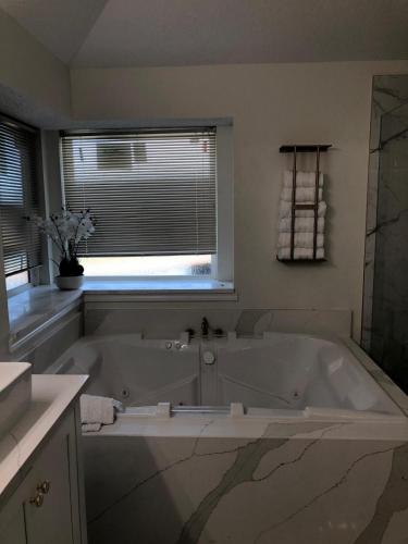 メスキートにあるLuxurious Villa Mesquite 3BD 2BA with Poolの窓付きのバスルーム(大きな白いバスタブ付)