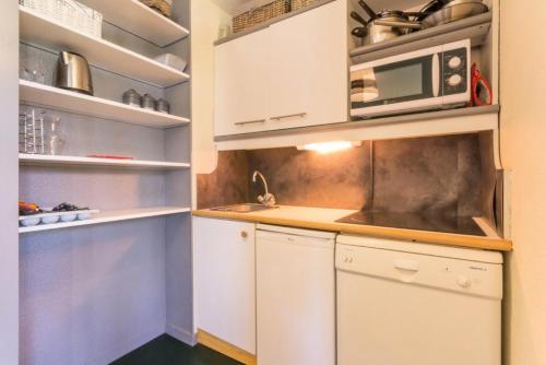 une cuisine avec des armoires blanches et un micro-ondes dans l'établissement Résidence Le De 3 - Bel appartement en rez de jardin MAE-4784, à Aime La Plagne