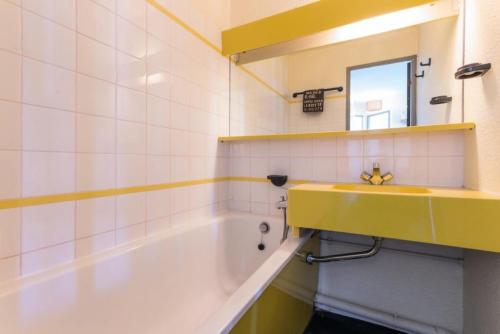 La salle de bains est pourvue d'un lavabo jaune et d'une baignoire. dans l'établissement Résidence Le De 3 - Bel appartement en rez de jardin MAE-4784, à Aime La Plagne