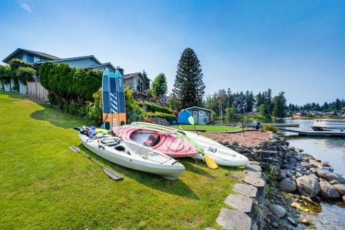 three boats sitting on the grass next to the water at The Rookery - Dreamy Home with Private Dock! in Yelm
