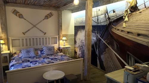 a room with a bed and a painting of a ship at T.H.NY Village Inn Cottage in Tihany
