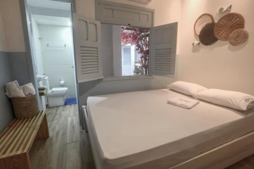 a white bedroom with a bed and a window at Vila DuJu in Porto De Galinhas