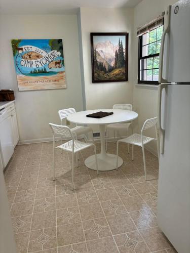 a kitchen with a white table and chairs and a refrigerator at Welcome to Camp Sycamore in Pittsburgh