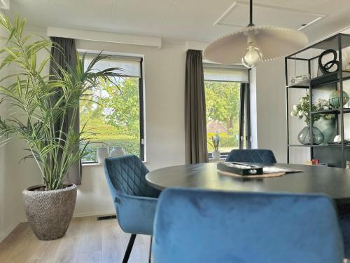 a dining room with a table and blue chairs at Vakantiehuis 't Hofje nabij dorpscentrum en strand in Castricum