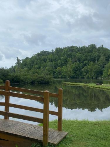 a wooden bench next to a body of water at River Run Cottage Modern 2BR Waterfront Retreat in Linville Land Harbor in Newland
