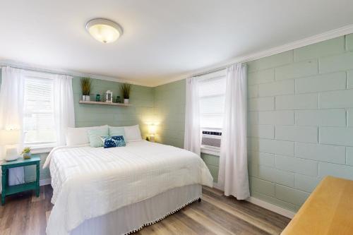 a bedroom with a white bed and two windows at Miller Time in Atlantic Beach