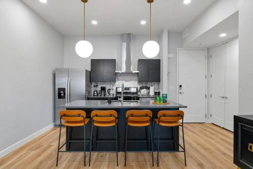 a kitchen with a black island with orange bar stools at Prime location - downtown SLC apt - ALL NEW in Salt Lake City