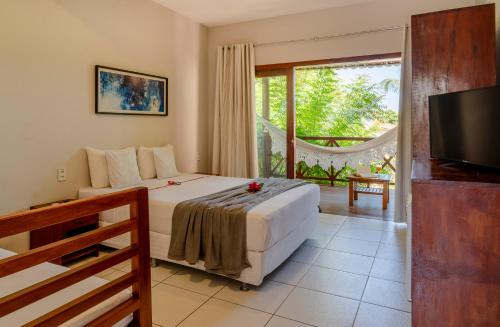 a hotel room with a bed and a television at Casa Suiça Brasileira in Jericoacoara