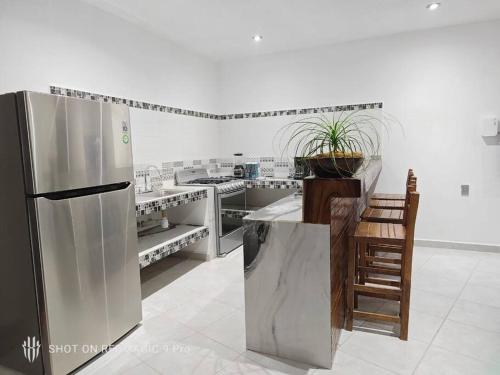 プエルト・バジャルタにあるDepartamento del Cualeのキッチン(ステンレス製の冷蔵庫、椅子付)