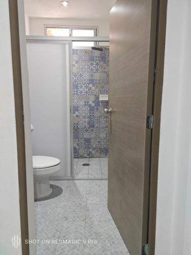 a bathroom with a toilet and a glass door at Departamento del Cuale in Puerto Vallarta