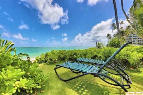 a blue bench sitting on the grass near the beach at Luxury One-Bedroom Apartment with Ocean View in Hauula