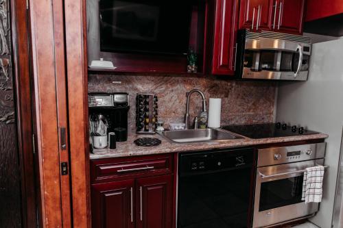 a small kitchen with red cabinets and a sink at Ski-in-out, Canyons, Westgate, King, Breakfast, HT in Park City
