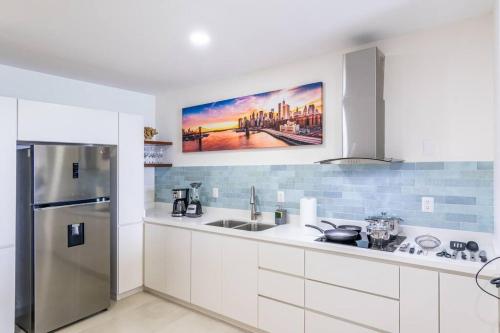 a kitchen with white cabinets and a stainless steel refrigerator at Hermoso Depa lujoso Cristal Bay Sobre el Malecon in Mazatlán