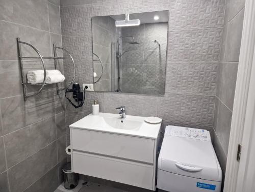 Un baño blanco con lavabo y espejo. en Fairways Club - TEIDE VIEW OASIS - heated pool, family apt, en San Miguel de Abona