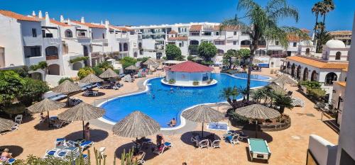 un complejo con una piscina con sombrillas en Fairways Club - TEIDE VIEW OASIS - heated pool, family apt, en San Miguel de Abona