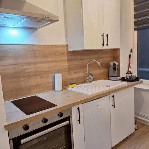une cuisine avec des armoires blanches et un évier dans l'établissement Studio 1er étage - Centre-ville - Local vélos disponible, à Mayenne