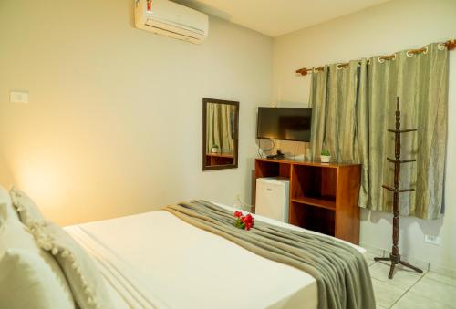 a hotel room with a bed and a television at Casa Suiça Brasileira in Jericoacoara