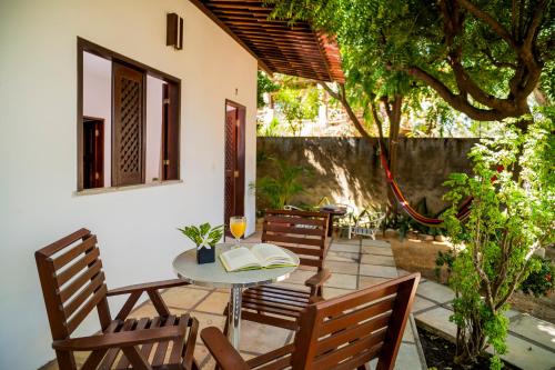 a table and chairs on a patio with a glass of wine at Casa Suiça Brasileira in Jericoacoara