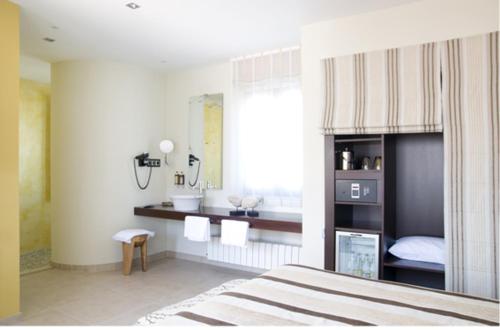 een slaapkamer met een bed en een badkamer met een wastafel bij Hotel Mar d'Espills - Adults Only in El Poblenou del Delta