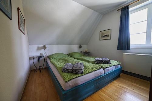 a bedroom with a bed with green sheets and a window at Nis-Puk in Norddorf