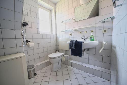 a white bathroom with a toilet and a sink at Nis-Puk in Norddorf