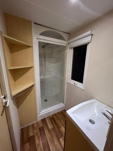 La salle de bains est pourvue d'une douche et d'un lavabo blanc. dans l'établissement mobil home, à Saint-Chéron