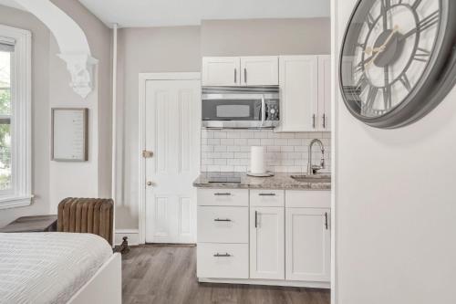 a kitchen with white cabinets and a clock on the wall at Trolley Teacup Charming Cozy Studio apts in Wilmington