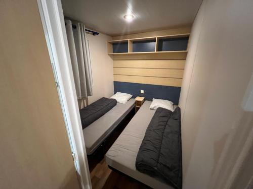 deux lits dans une petite pièce avec une fenêtre dans l'établissement mobil home, à Saint-Chéron