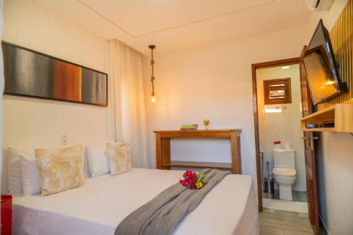 a bedroom with a white bed with flowers on it at Casa Suiça Brasileira in Jericoacoara