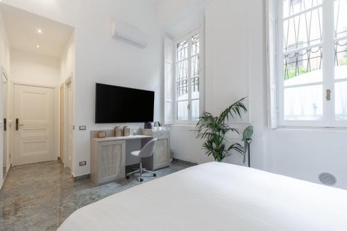 a white bedroom with a desk and a tv at Duomo Smart Suites in Milan