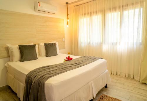 a bedroom with a large white bed with a red flower on it at Casa Suiça Brasileira in Jericoacoara