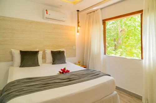 a bedroom with a large white bed with a window at Casa Suiça Brasileira in Jericoacoara
