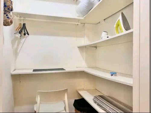 ein weißer Schrank mit einem weißen Stuhl und Regalen in der Unterkunft Departamento en Microcentro Ciudad de Buenos Aires in Buenos Aires