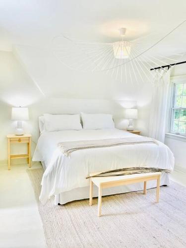 a white bedroom with a large bed and a table at Waterfront Niagara-On-The-Lake Farmhouse on a Vineyard in Niagara on the Lake