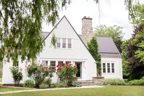 a white house with flowers in the front yard at Waterfront Niagara-On-The-Lake Farmhouse on a Vineyard in Niagara on the Lake