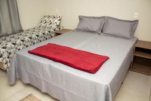 a bed with a red blanket on top of it at Pousada Vila Rose Express Loft in Nobres