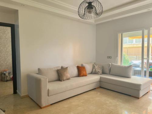 a living room with a couch with pillows on it at Studio Résidence Les Jardins de Tamaris in Sidi Rahal