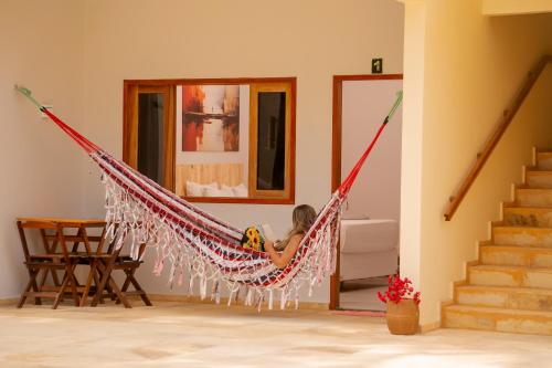 a woman sitting in a hammock in a room at Casa Suiça Brasileira in Jericoacoara
