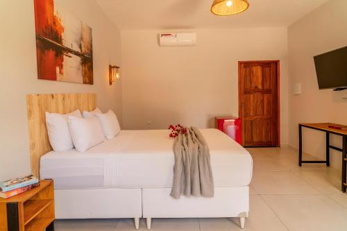 a bedroom with a large white bed and a television at Casa Suiça Brasileira in Jericoacoara