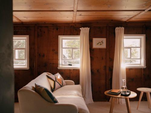 a living room with a couch and two windows at Sandbur Das Walserhaus in Lech am Arlberg