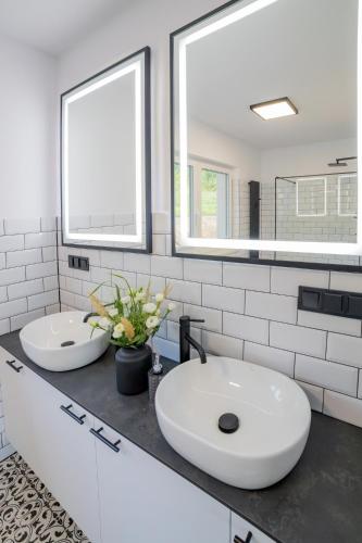 a white bathroom with two sinks and two mirrors at Siedlisko Przy Lesie Alpaka 3 in Workiejmy