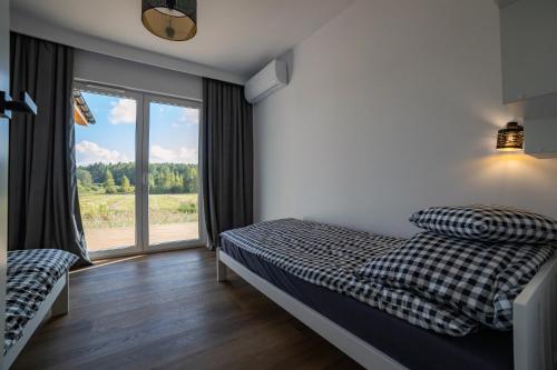 a bedroom with a bed and a large window at Siedlisko Przy Lesie Alpaka 3 in Workiejmy