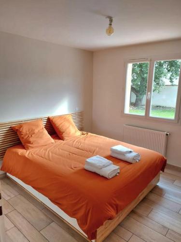 - une chambre avec un lit orange et 2 serviettes dans l'établissement T3 climatisé, parking et jardin quartier des Marots à Colomiers, à Colomiers