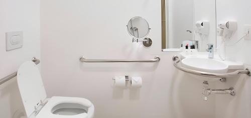 a white bathroom with a toilet and a sink at Ramada by Wyndham Campinas Viracopos in Campinas