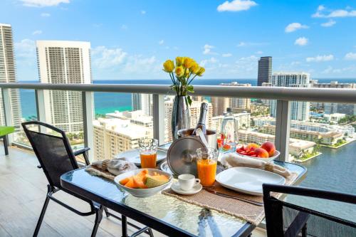 a table with food and drinks on a balcony at Ocean Views - Pool & Gym - Pet Friendly - Close to Beach in Hallandale Beach