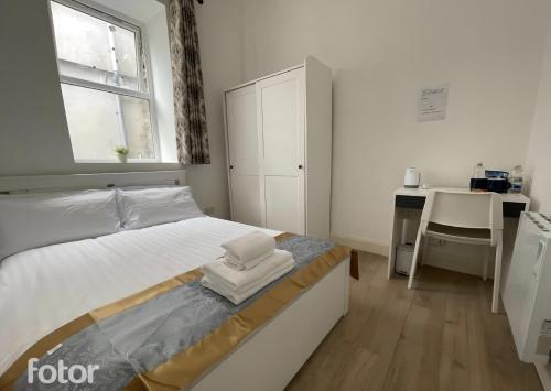 a white bedroom with a bed and a desk at Leitrim Property Cork in Cork