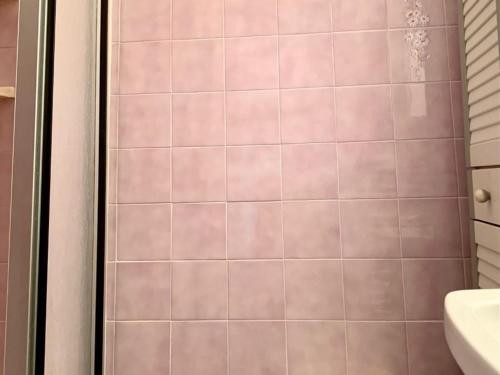 La salle de bains est pourvue d'une douche et de carrelage rose. dans l'établissement Appartement Duplex à Mèze avec Terrasse et Garage Proche Port et Plage - 2 Clés - FR-1-604-30, à Mèze