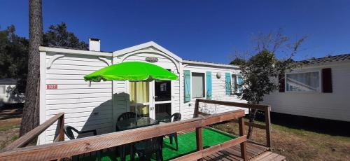 a house with a green umbrella on a deck at Bungalows 2XZ ou 327 in Burinhosa