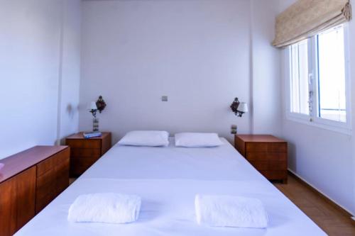 a bedroom with a large white bed and a window at Astali Villa in Stalida